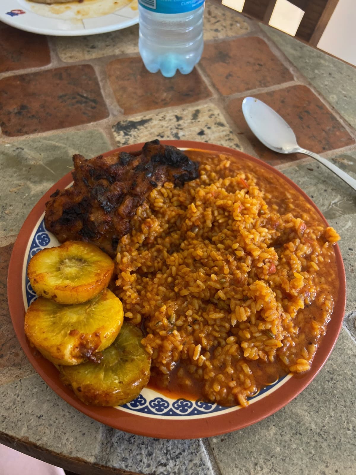 Prato de arroz jollof nigeriano de festa com banana frita e frango